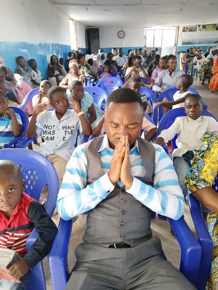 Men, women and children in prayer at an NCE church